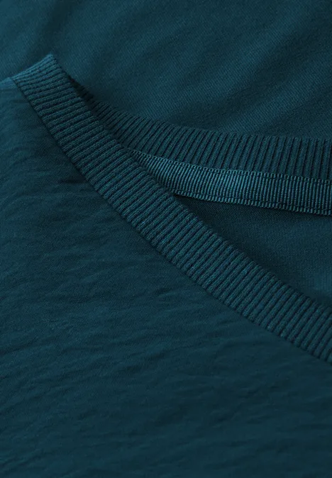 Nahaufnahme eines dunkelgrünen T-Shirt-Kragens aus Baumwolle.